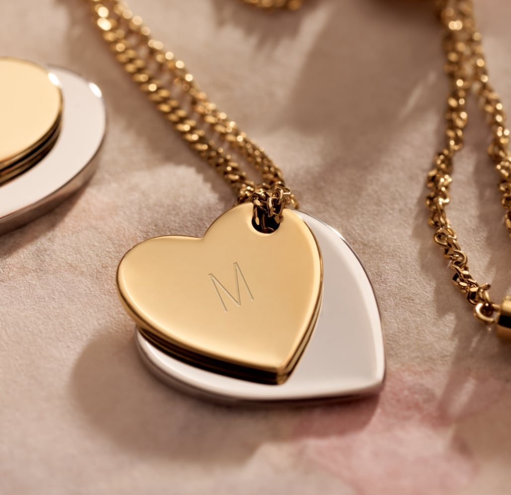 A heart necklace with M engraved on it. 