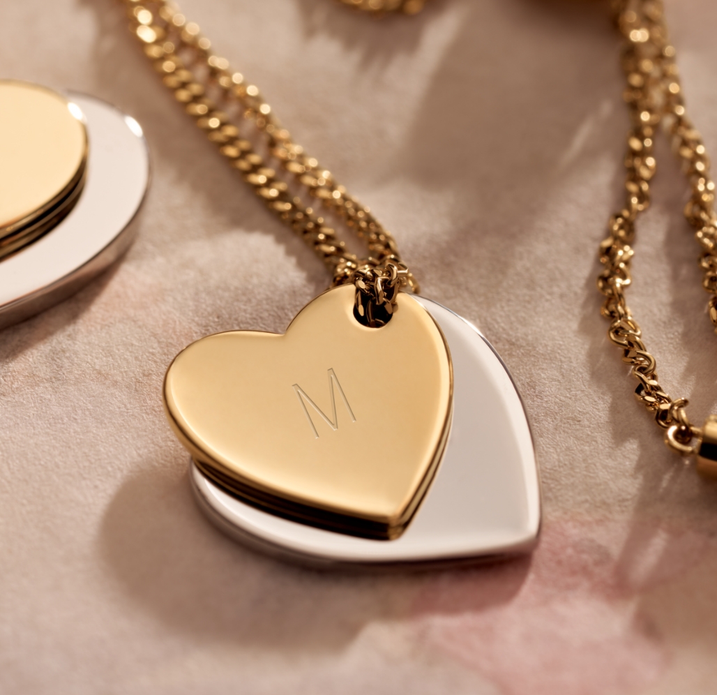 A heart necklace with M engraved on it. 