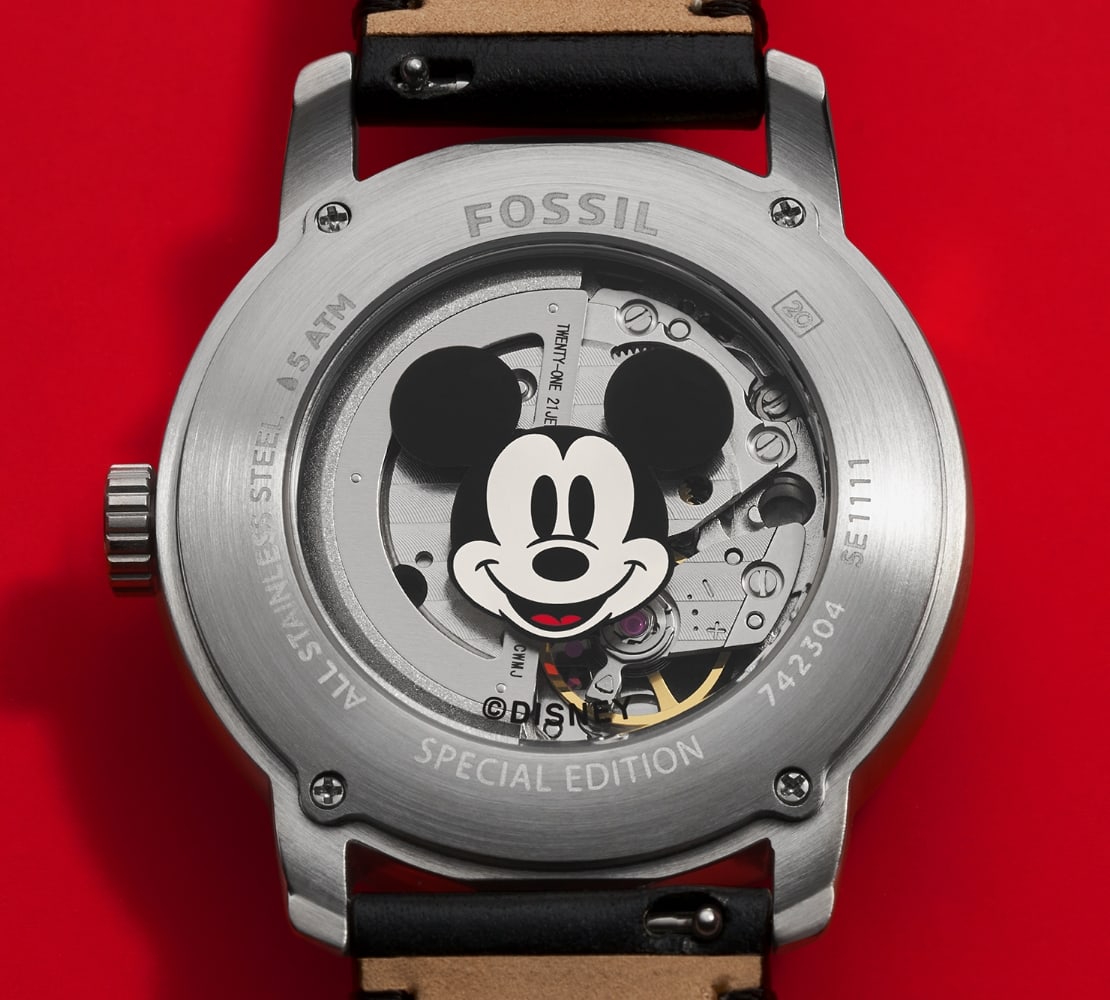 Vue détaillée du dos du boîtier de la montre, avec le visage souriant de Mickey, laissant entrevoir le mouvement automatique Japonais.
