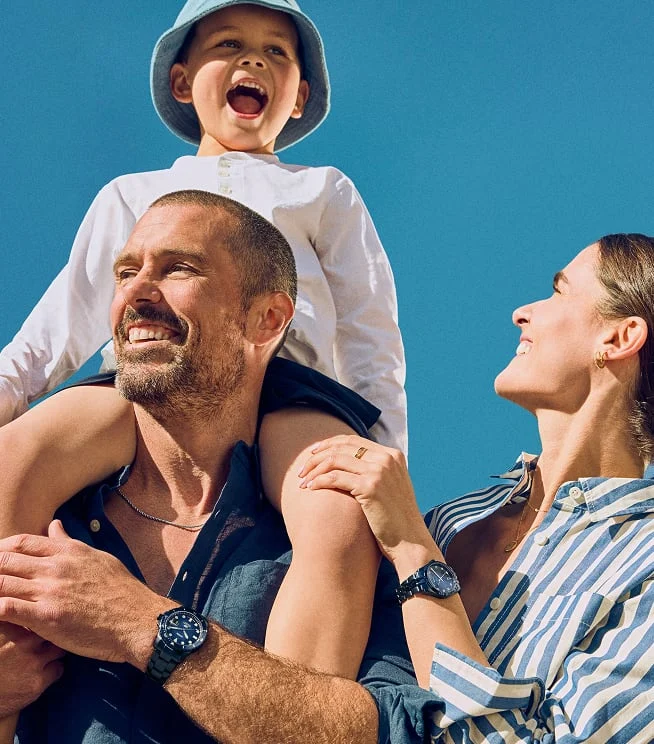 A candid photo of a dad carrying his son on his shoulders alongside his wife.