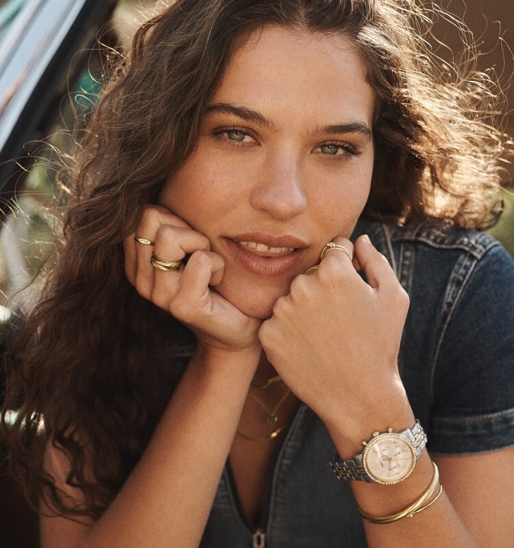 A woman sitting in a car and wearing a Neutra Chronograph and jewellery from our autumn collection.