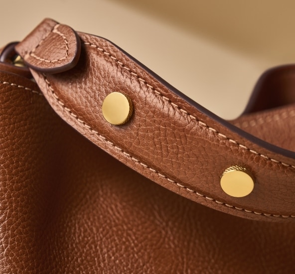 The brown leather strap with gold-tone rivets, showcasing the subtle texture from our Signature Knurling.