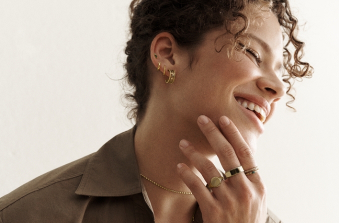 Frau mit goldfarbenen Ringen, Uhr und Armbändern.