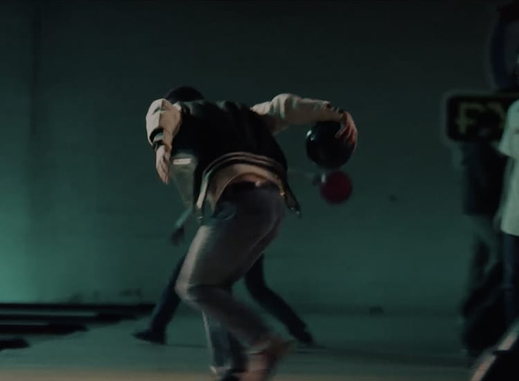 An action shot of Nick Jonas bowling.