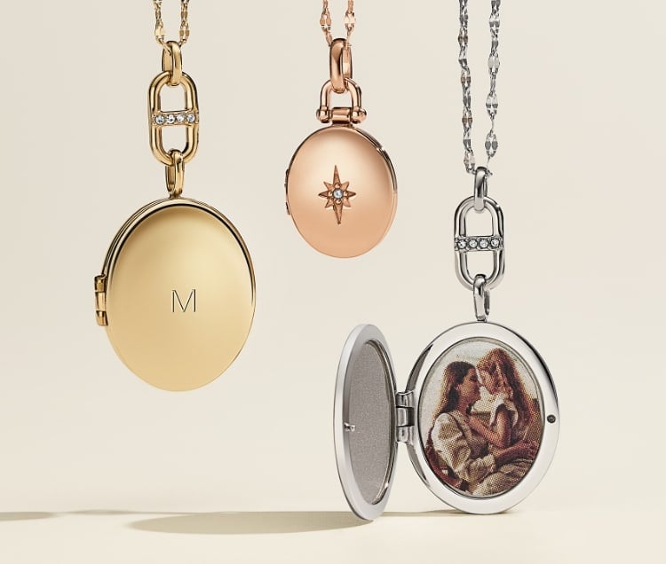 A gold-tone locket engraved with the letter M; a rose gold-tone locket with crystals on the cover; and a silver-tone locket, open to reveal a photo inside.