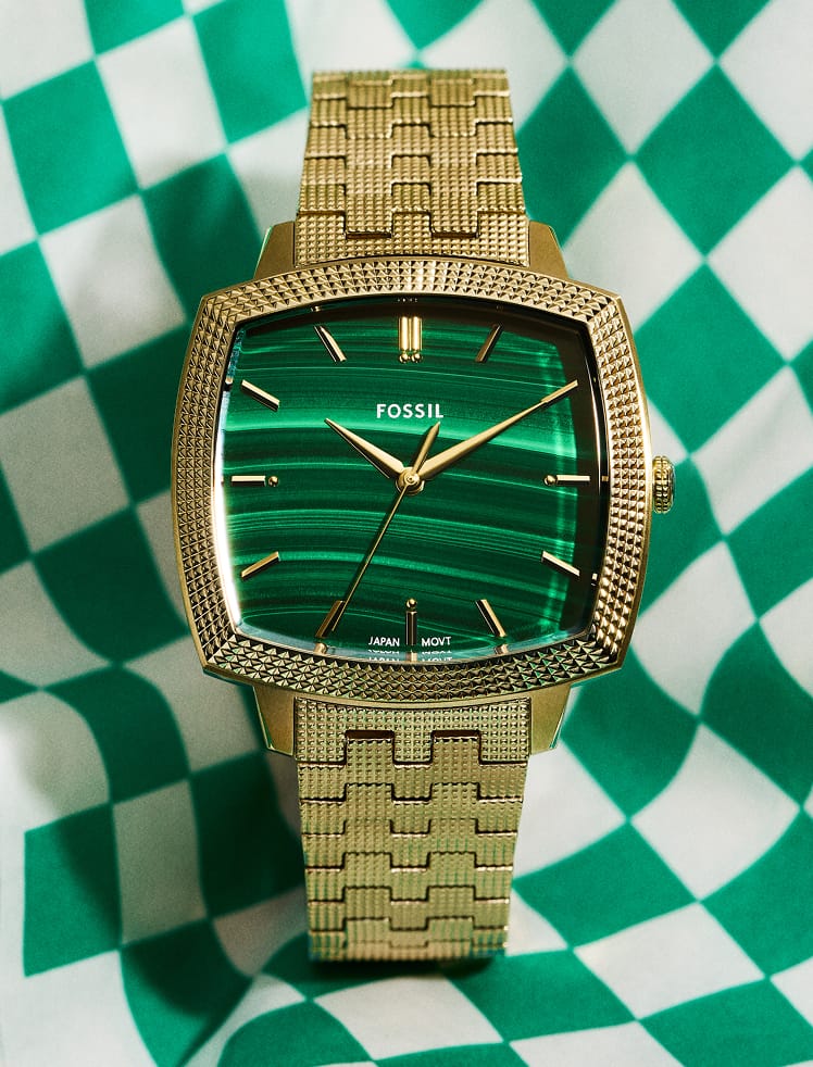 A close-up of the watch on a green checkerboard backdrop.