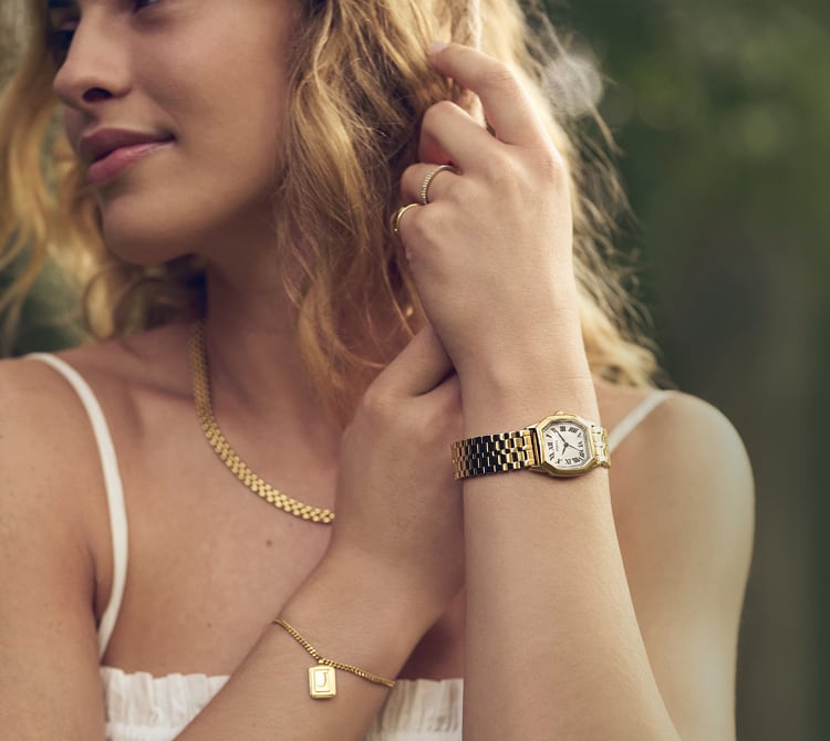 A woman wearing a breezy white sundress and delicate Fossil gold-tone jewellery, paired with the Fossil Harlow watch.
