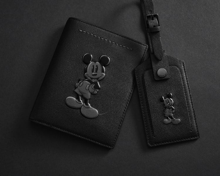 A black leather passport holder and luggage tag featuring the silhouette of Disney's Mickey Mouse.