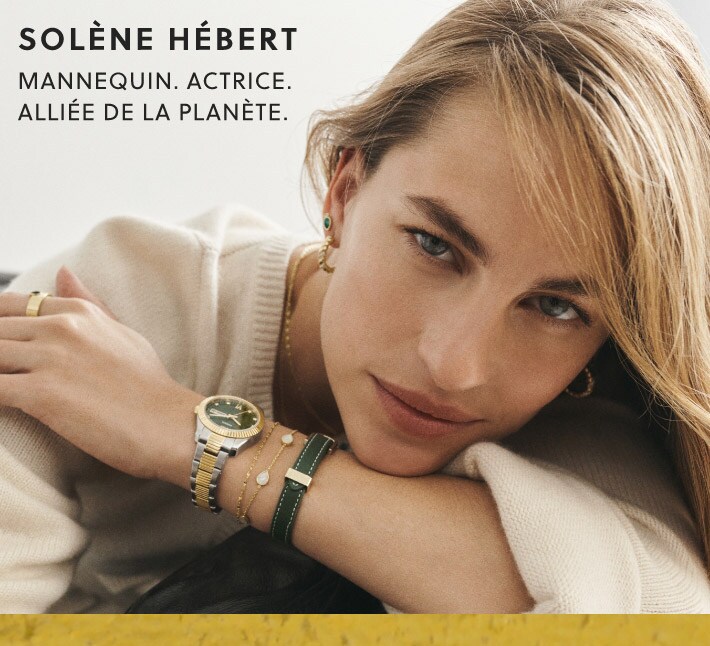 Solène Hébert pose avec des bijoux dorés et verts assortis à sa montre Scarlette et des créoles torsadées