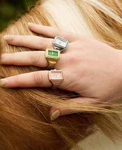 A woman wearing watch rings stacked on multiple fingers of both hands.