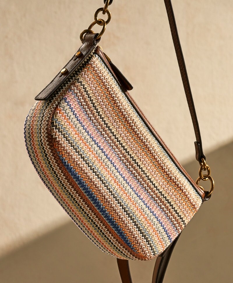 The striped Jolie baguette hanging from a brown leather strap.