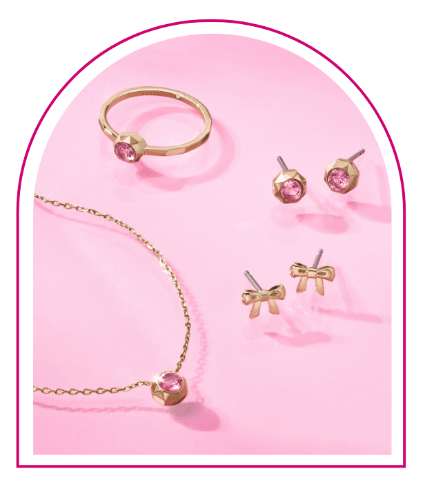 Ein pinker Hintergrund mit einem Fenster im Stil des Traumhauses von Barbie™. Im Fenster sieht man Styles aus unserer Limited Edition Barbie™ x Fossil Schmuckkollektion: eine goldfarbene Halskette mit passendem Ring und Ohrsteckern, alle mit stylishen pinken Glassteinverzierungen.