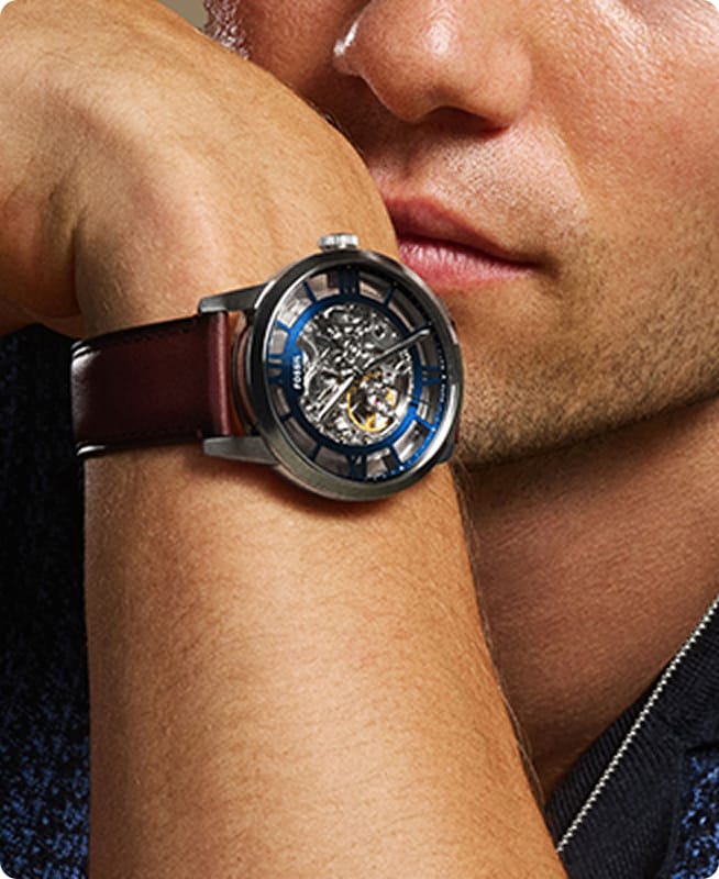 A man dressed in a blue knit sweater wearing the Townsman watch in a blue-finished dial and brown leather strap.