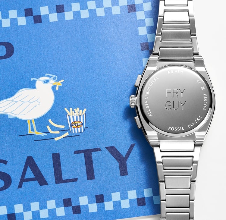 An illustrated postcard of a seagull wearing sunglasses, eating fries on the beach. It is shown alongside the caseback of a Fossil watch, engraved with the words FRY GUY.