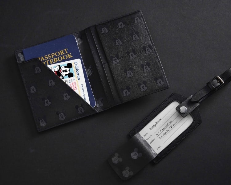 A black leather passport holder and luggage tag featuring the silhouette of Disney’s Mickey Mouse.