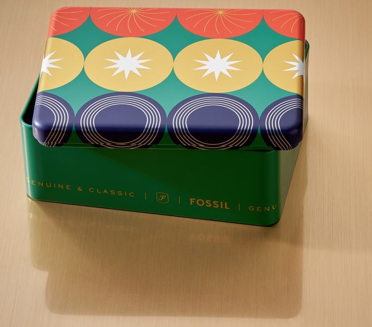 Gif of a brightly colored Fossil gift set tin opening to reveal a men's brown leather watch and brown leather bracelet. 
