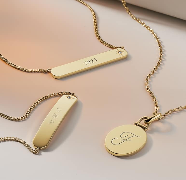 A group of various gold-tone necklaces, each with an engraving.