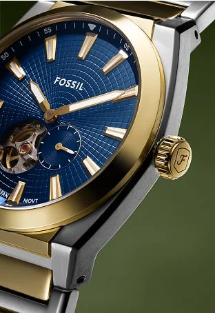 A close-up of the sleek and sporty Everett automatic watch on the wrist of a stylish man, featuring a gold-tone finish with a green textured dial.