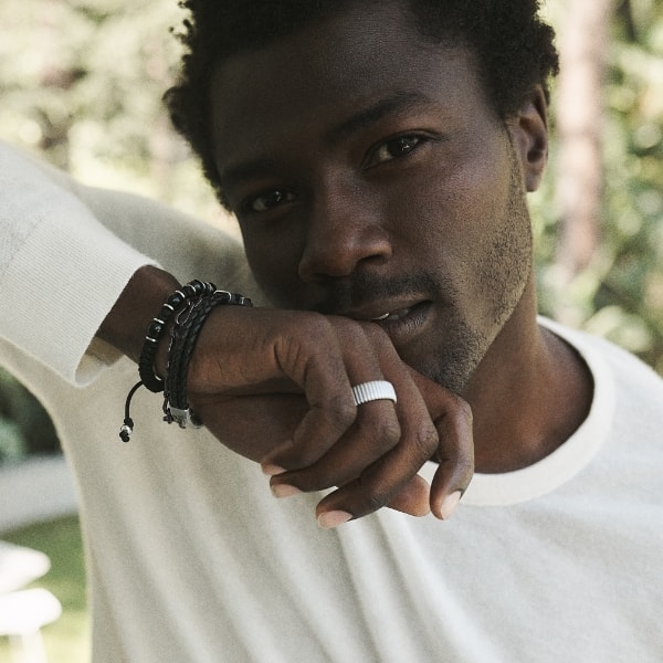 A man in a white shirt wearing the latest men's jewelry styles.