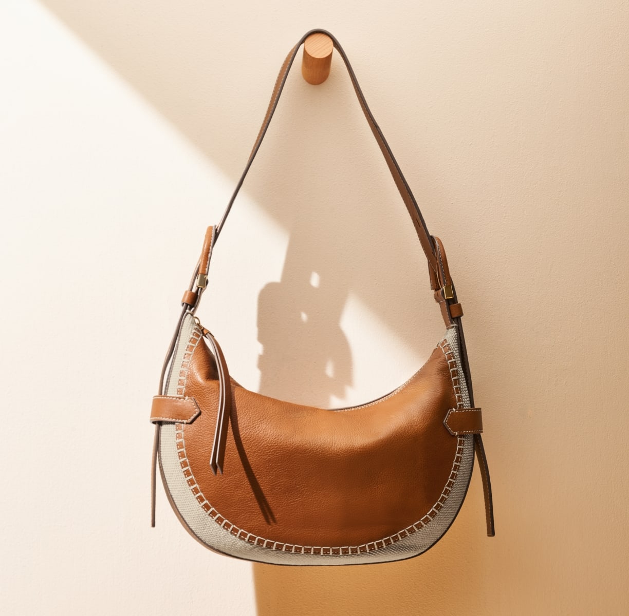 A GIF of the Harwell leather and cotton bag with a closeup of its leather-wrapped buckle detail.
