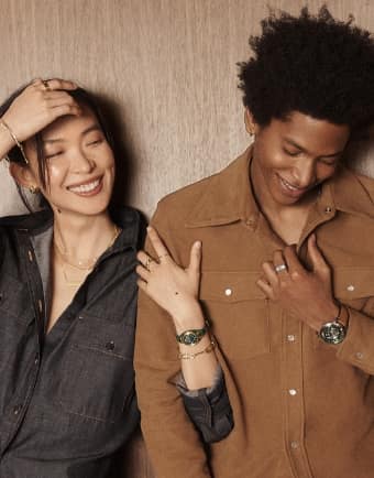 A woman and a man smiling and wearing Fossil watches. 