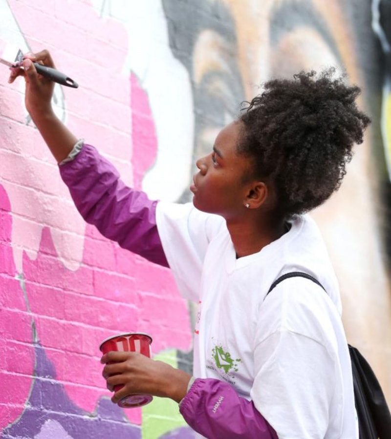 A young woman painting a mural