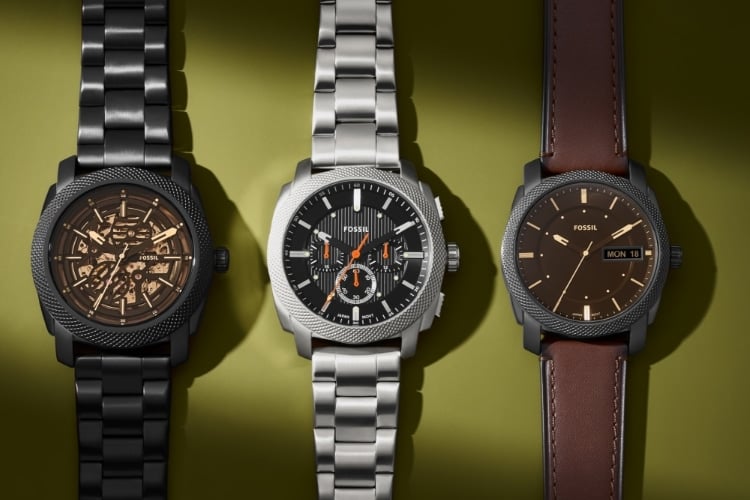 A close-up view of three Fossil Machine watches: automatic, chronograph and three-hand on an olive green background.