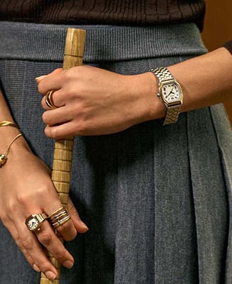 A lifestyle image of a woman wearing a gold-tone Harlow watch with a black dial.