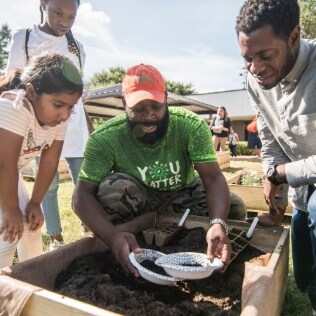 A man and two children at a community garden.
