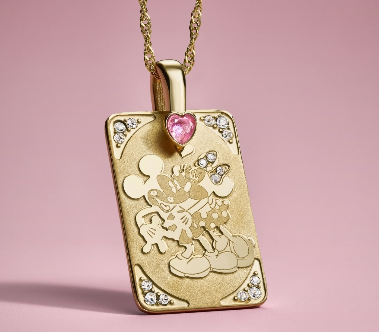 Le collier pendentif doré à l’effigie de Mickey et Minnie, rehaussé de cristaux.