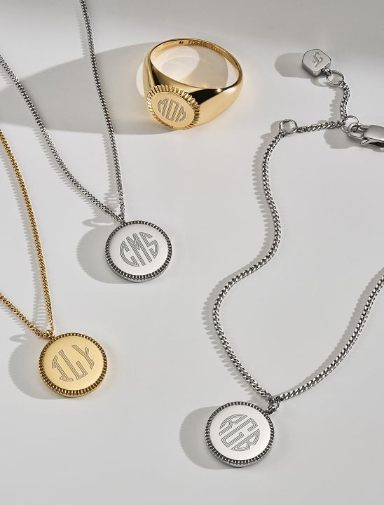 Des colliers pendentifs personnalisés et une chevalière gravée d’une initiale dans des finitions dorées et argentées