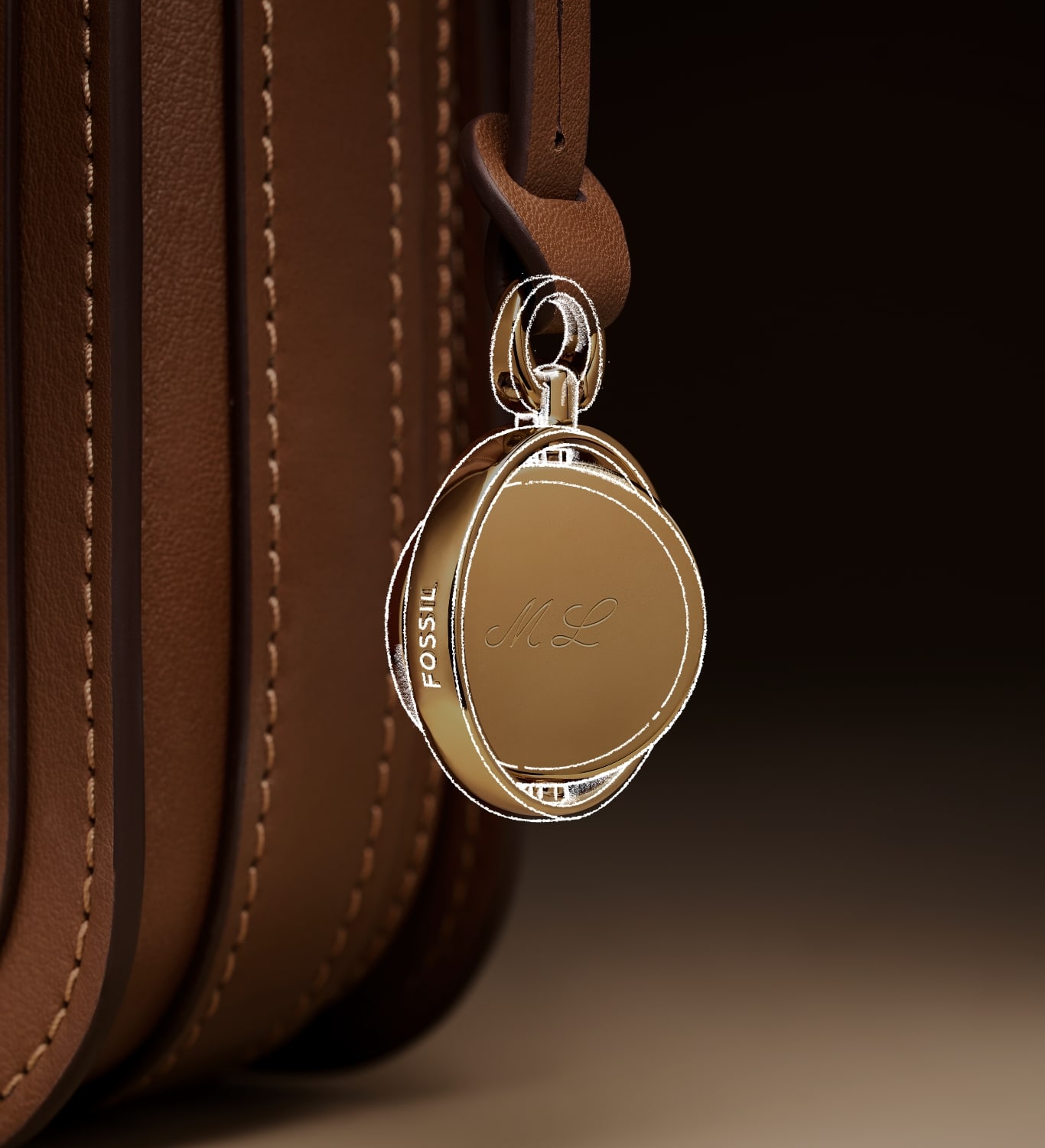 The gold-tone Legacy Charm hanging from the brown leather Lennox bag and engraved with ML. Overlayed with a sketch.