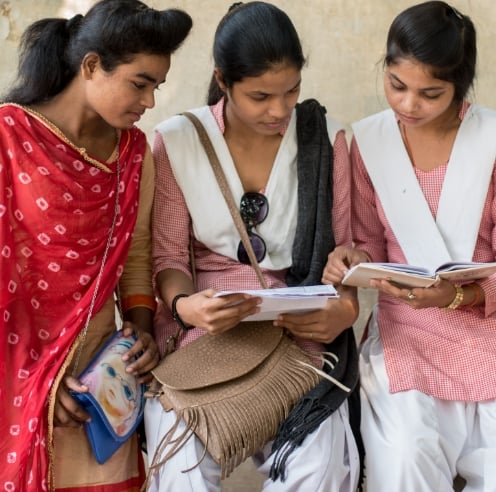 Trois jeunes filles assises ensemble et souriant.