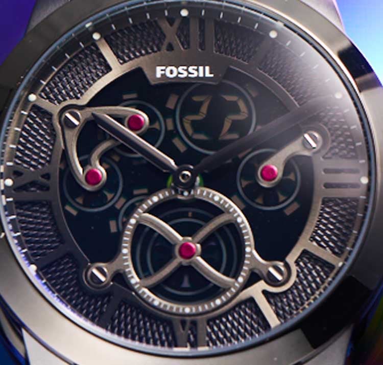 The Fossil Townsman Big Tic watch shown against a kaleidoscopic background.