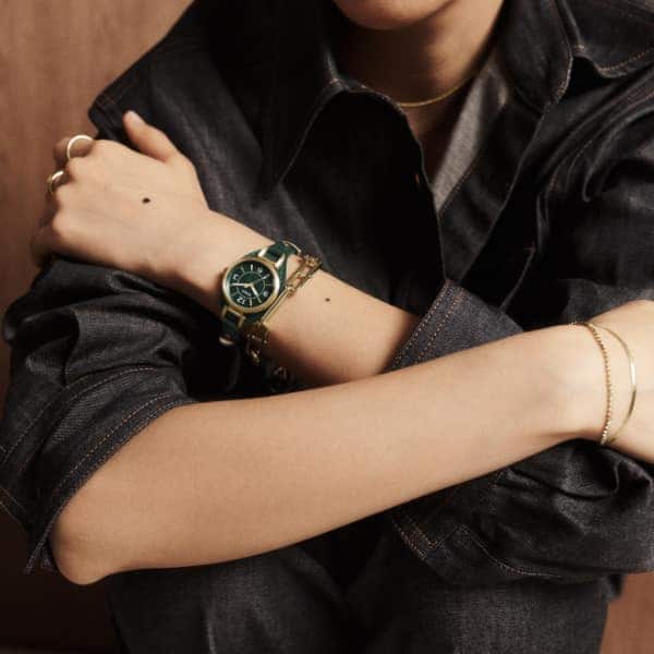 Une femme portant la montre Carlie, avec son bracelet à point sellier en cuir vert.
