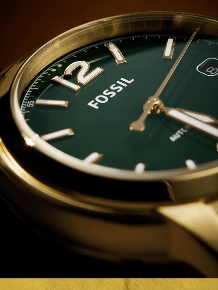 A close-up of a woman’s Fossil Heritage watch with a green dial.