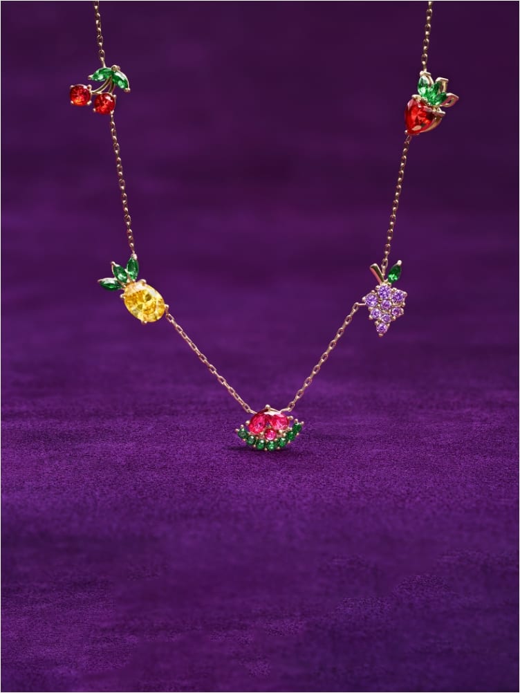 A GIF highlighting the gold-tone necklace featuring colorful fruit crystals and the earring set of five fruit-shaped crystals.