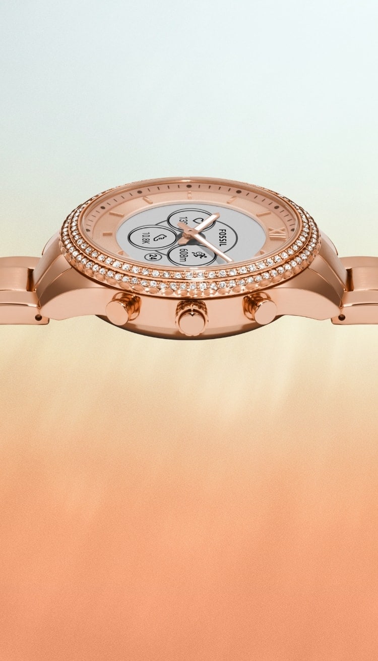 Un gros plan de la montre connectée Gen 6 hybride doré rose avec un cadran qui affiche une notification pour assister à une fête.