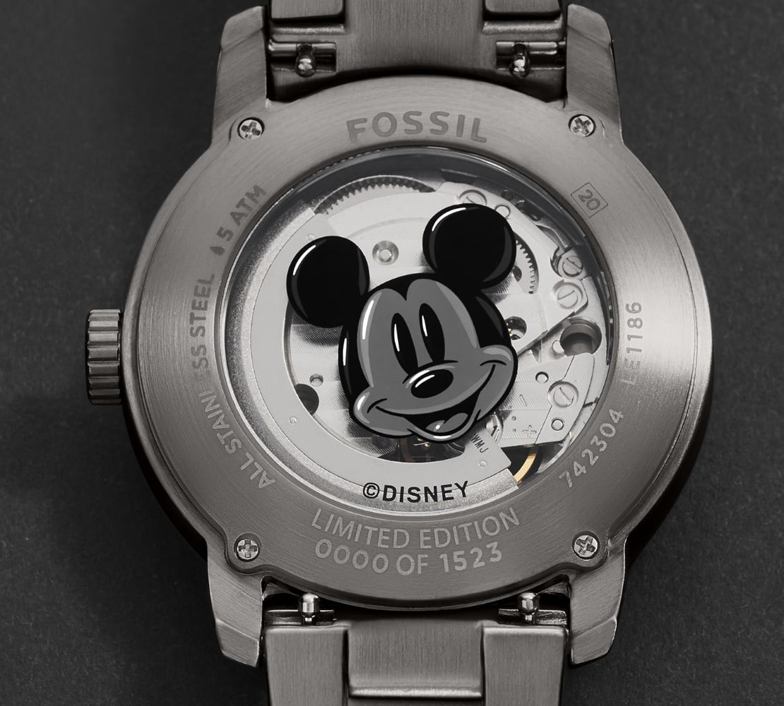 Vue détaillée du dos du boîtier de la montre, avec le visage souriant de Mickey, laissant entrevoir le mouvement automatique Japonais.