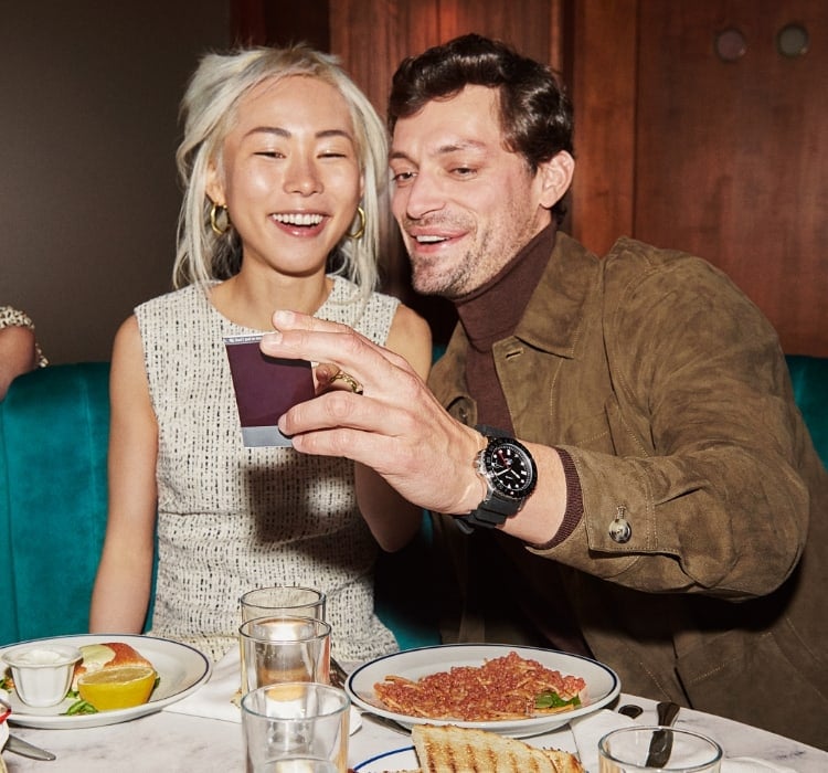 A man and a woman looking at a photo. He is wearing the Fossil Blue GMT.