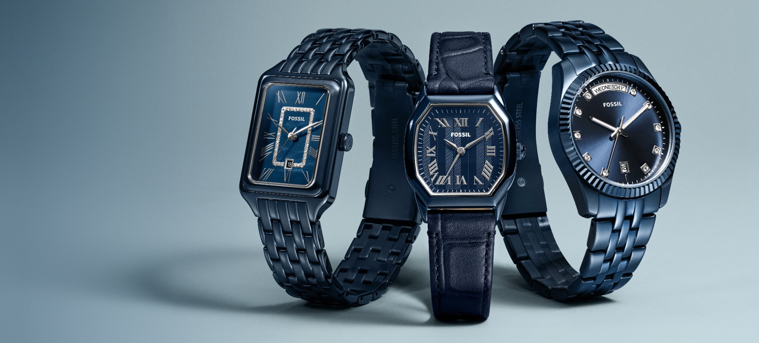 Three navy blue-toned Fossil watches – A Raquel, Harlow, and Scarlette – appear side-by-side on a light blue background.