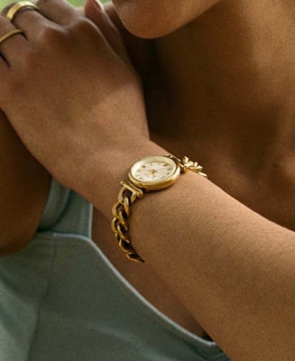A lifestyle image of a woman crossing her arms, wearing the Carlie watch and a delicate bracelet.